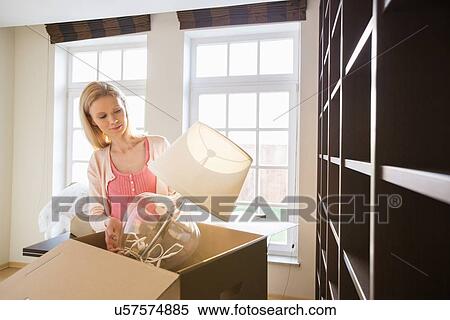 Woman removing lamp from cardboard box at new home View Large Photo Image Stock Photography - Woman removing lamp from cardboard box at new home. Fotosearch