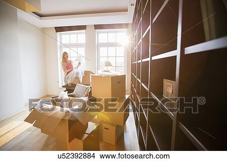 Picture - Woman unpacking lamp from moving box at new house. Fotosearch