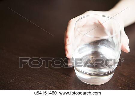 Woman's hand holding glass of water on table View Large Photo Image Stock Image - Woman's hand holding glass of water on table. Fotosearch