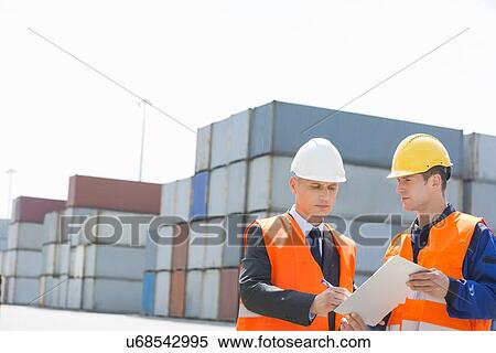 Worker taking sign of supervisor on clipboard in shipping yard View Large Photo Image Stock Photography - Worker taking sign of supervisor on clipboard in shipping yard. Fotosearch