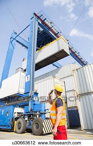 Worker using walkie-talkie in shipping yard View Large Photo Image Stock Image - Worker using walkie-talkie in shipping yard. Fotosearch