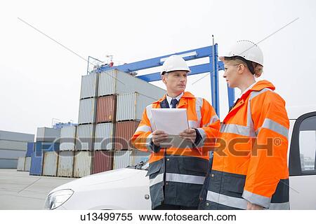 Workers conversing in shipping yard View Large Photo Image Stock Photography - Workers conversing in shipping yard. Fotosearch