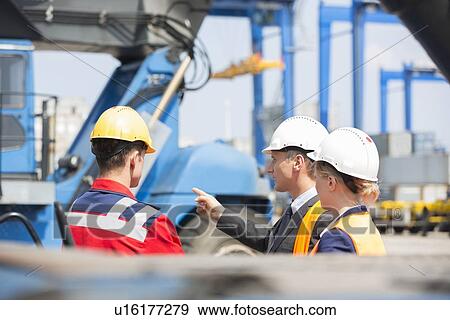 Stock Photo - Workers discussing in shipping yard. Fotosearch