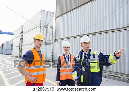 Stock Photo - Workers discussing in shipping yard. Fotosearch