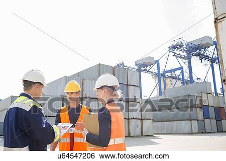 Stock Photograph - Workers discussing in shipping yard. Fotosearch