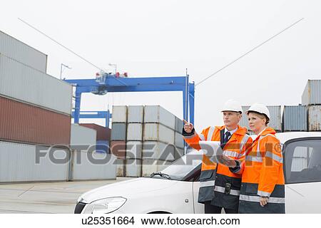 Picture - Workers examining cargo in shipping yard. Fotosearch