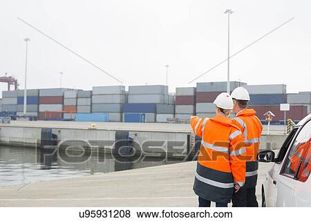 Workers in protective clothing examining cargo in shipping yard View Large Photo Image Stock Photo - Workers in protective clothing examining cargo in shipping yard. Fotosearch