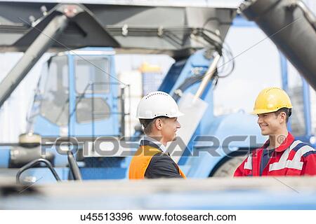 Stock Photograph - Workers shaking hands in shipping yard. Fotosearch