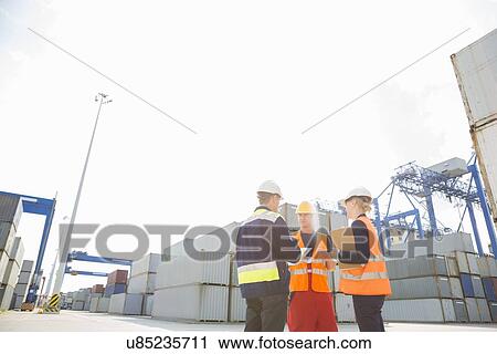 Stock Image - Workers talking in shipping yard. Fotosearch