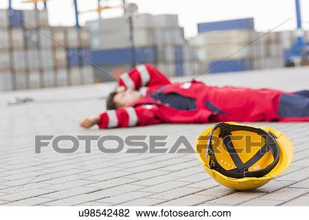 Yellow hardhat at shipyard with depressed male worker lying in shipping yard View Large Photo Image Stock Image - Yellow hardhat at shipyard with depressed male worker lying in shipping yard. Fotosearch