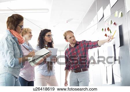 Young businessman explaining document to female colleagues in creative office View Large Photo Image Stock Photo - Young businessman explaining document to female colleagues in creative office. Fotosearch