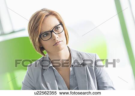 Stock Photography - Young businesswoman looking away in office. Fotosearch