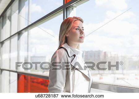 Stock Photo - Young businesswoman looking through glass at railroad station. Fotosearch