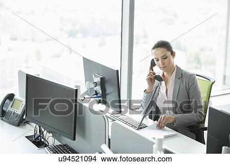 Young businesswoman talking on telephone in office View Large Photo Image Picture - Young businesswoman talking on telephone in office. Fotosearch