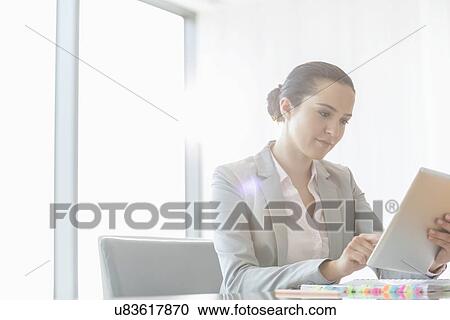 Young businesswoman using digital tablet in office View Large Photo Image Stock Image - Young businesswoman using digital tablet in office. Fotosearch