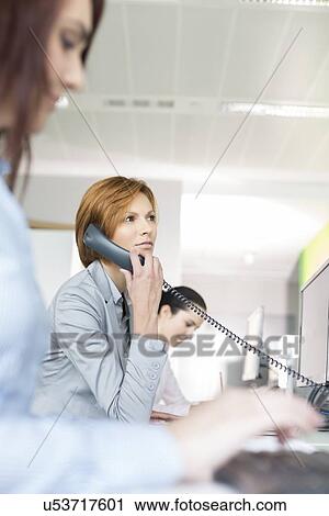Young businesswoman using landline phone in office View Large Photo Image Stock Image - Young businesswoman using landline phone in office. Fotosearch