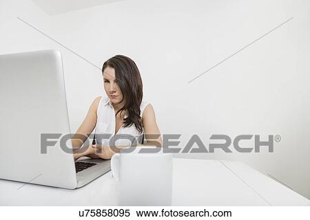 Young businesswoman using laptop at desk in office View Large Photo Image Stock Photography - Young businesswoman using laptop at desk in office. Fotosearch