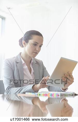 Stock Photograph - Young businesswoman using tablet PC in office. Fotosearch