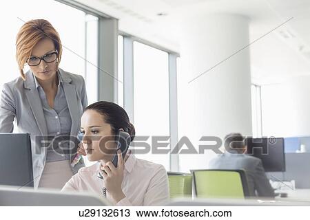 Stock Image - Young businesswomen working in office. Fotosearch