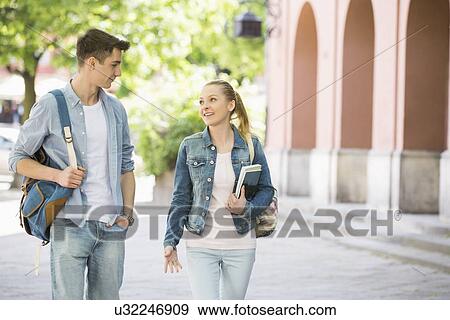 Stock Photo - Young college friends talking while walking at campus. Fotosearch