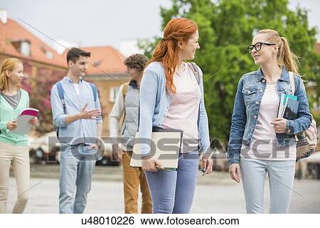 Stock Photograph - Young college friends walking on street. Fotosearch