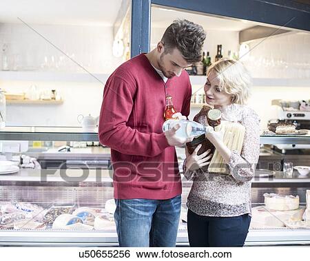 Young couple discussing over product outside cafe View Large Photo Image Stock Photograph - Young couple discussing over product outside cafe. Fotosearch