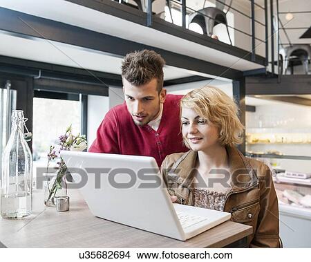Young couple using laptop in cafe View Large Photo Image Picture - Young couple using laptop in cafe. Fotosearch