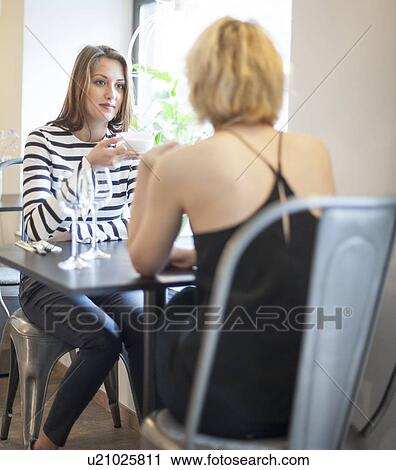 Young female friends having coffee at cafe View Large Photo Image Stock Image - Young female friends having coffee at cafe. Fotosearch