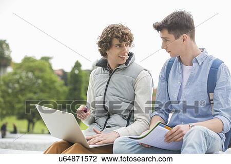 Young male college friends with laptop studying together in park View Large Photo Image Stock Image - Young male college friends with laptop studying together in park. Fotosearch