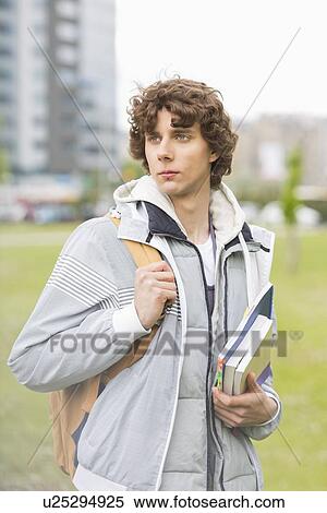 Young male university student holding textbooks at campus View Large Photo Image Stock Photography - Young male university student holding textbooks at campus. Fotosearch