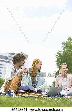Young man having coffee while studying with female friends at college campus View Large Photo Image Stock Image - Young man having coffee while studying with female friends at college campus. Fotosearch