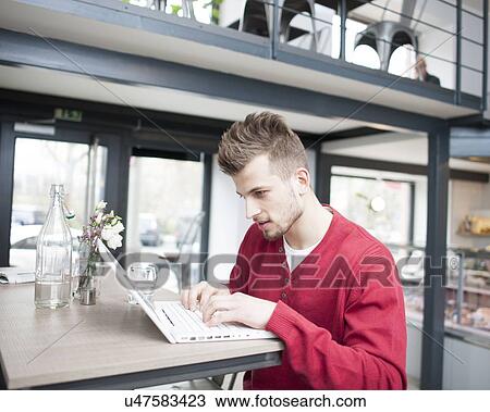 Young man using laptop in cafe View Large Photo Image Stock Image - Young man using laptop in cafe. Fotosearch