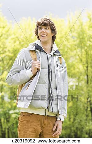 Young man with backpack standing at college campus View Large Photo Image Stock Image - Young man with backpack standing at college campus. Fotosearch