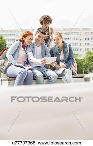 Stock Photo - Young students photographing themselves through digital tablet at campus. Fotosearch