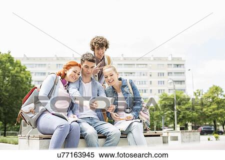 Young students photographing themselves through digital tablet at college campus View Large Photo Image Stock Photography - Young students photographing themselves through digital tablet at college campus. Fotosearch