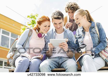 Young students using digital tablet at college campus View Large Photo Image Stock Photo - Young students using digital tablet at college campus. Fotosearch