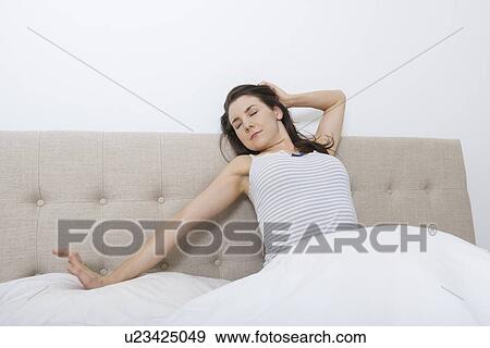 Young woman stretching in bed View Large Photo Image Stock Photo - Young woman stretching in bed. Fotosearch