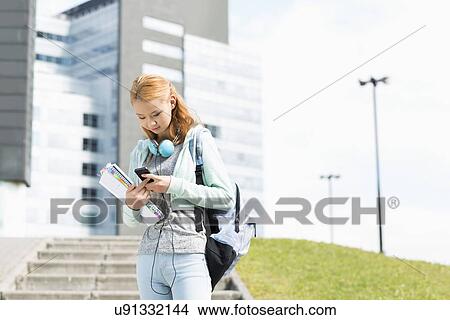 Young woman using smart phone at college campus View Large Photo Image Picture - Young woman using smart phone at college campus. Fotosearch
