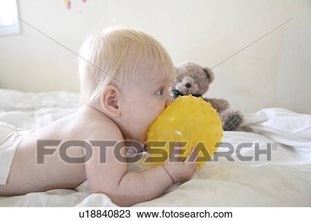 baby eats a yellow ball. View Large Photo Image Stock Image - baby eats a yellow ball.. Fotosearch