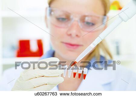 Stock Image - Female technician using a pipette. Fotosearch