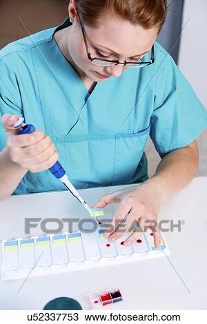 Stock Image - Lab technician using a pipette. Fotosearch
