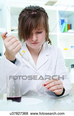 Stock Photo - Young woman using a pipette in a lab. Fotosearch