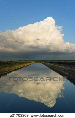 Stock Photo -  A cloud hanging over the dutch countryside at dusk. Fotosearch
