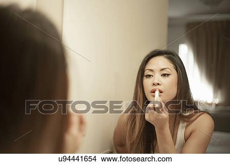 Attractive woman applying lipstick, looking in mirror View Large Photo Image Picture - Attractive woman applying lipstick, looking in mirror. Fotosearch