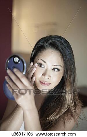 Stock Photography - Attractive woman using compact mirror to check make-up. Fotosearch