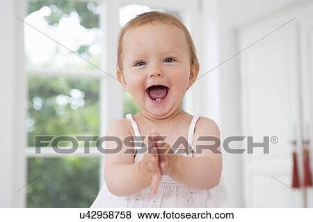 Stock Photo - Baby girl clapping hands, portrait. Fotosearch