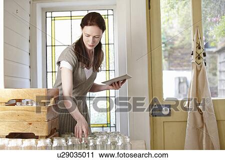 Beekeeper using digital tablet in kitchen whilst preparing jars View Large Photo Image Stock Image - Beekeeper using digital tablet in kitchen whilst preparing jars. Fotosearch