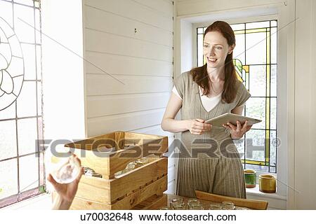Beekeeper using digital tablet in kitchen whilst unpacking jars View Large Photo Image Stock Photo - Beekeeper using digital tablet in kitchen whilst unpacking jars. Fotosearch