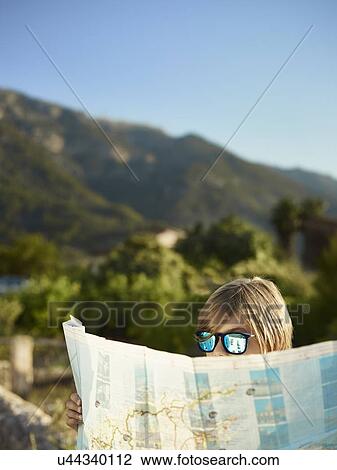 Stock Image - Boy in sunglasses looking at a map, Majorca, Spain. Fotosearch