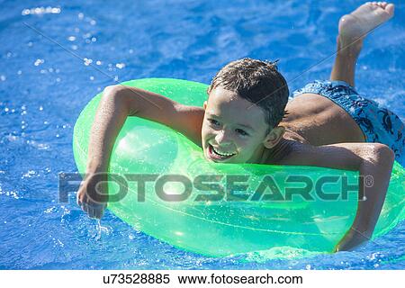 Boy lying on inflatable ring in garden swimming pool View Large Photo Image Stock Photography - Boy lying on inflatable ring in garden swimming pool. Fotosearch